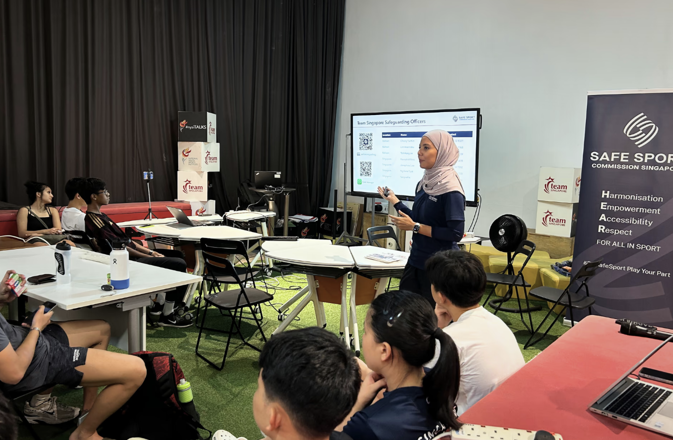  A woman stands before a group, delivering a presentation and interacting with her audience.